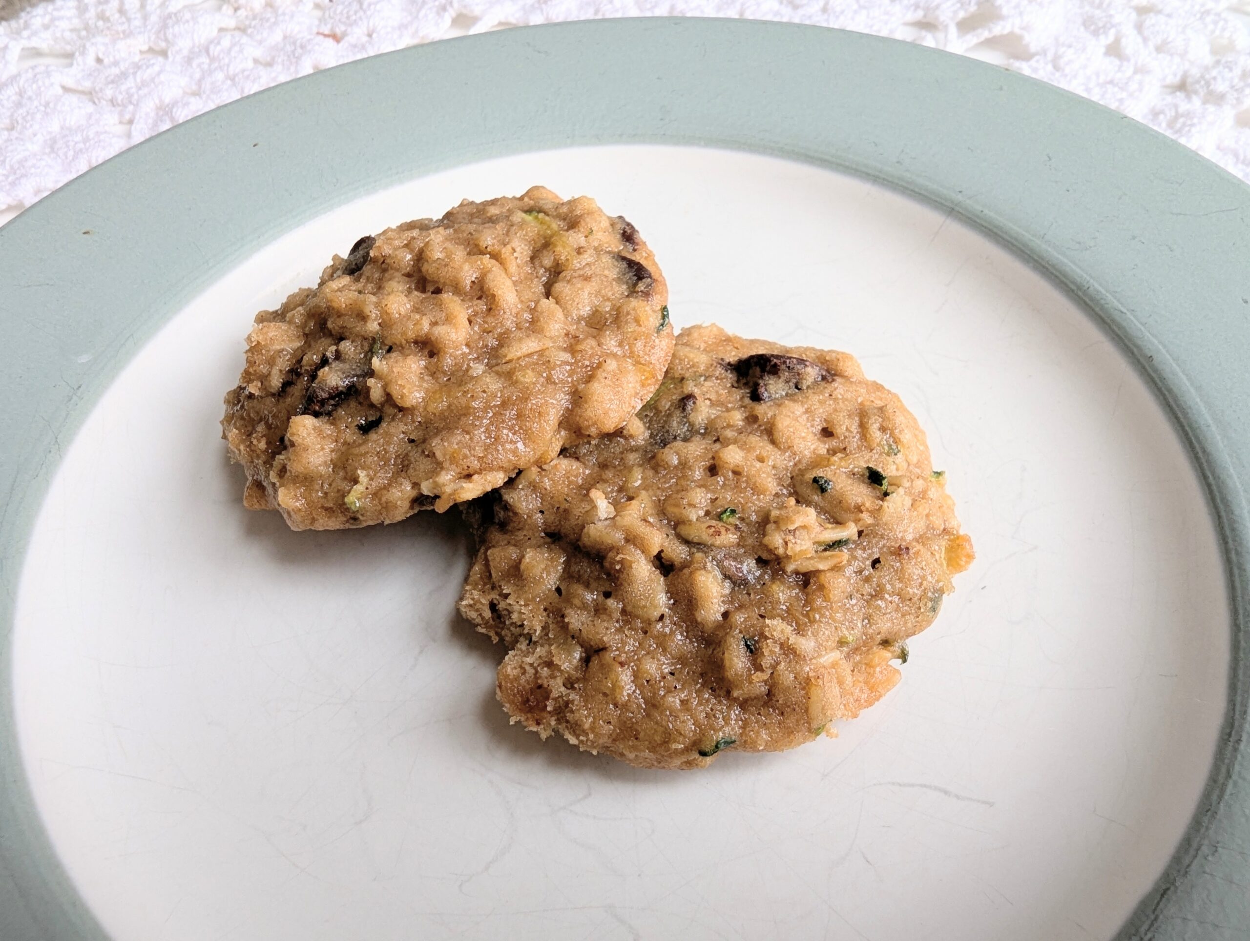 Two zucchini cookies on a sage colored plate